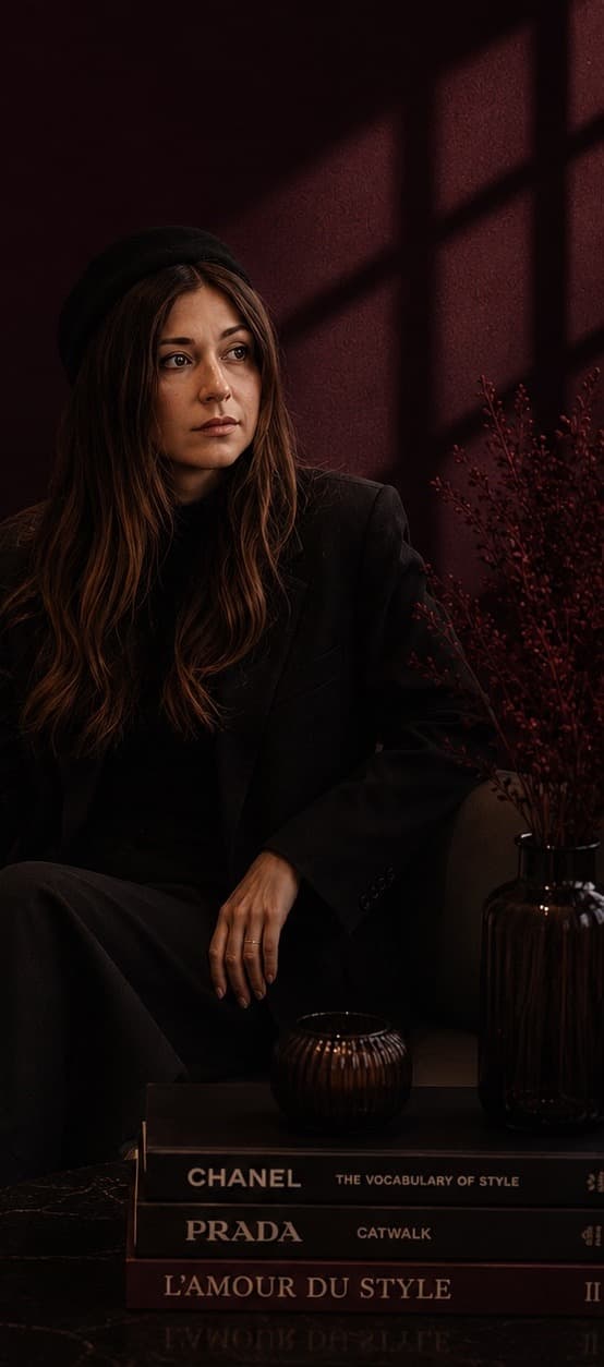 Daryna seated in a moody café setting, styled in a dark tailored outfit