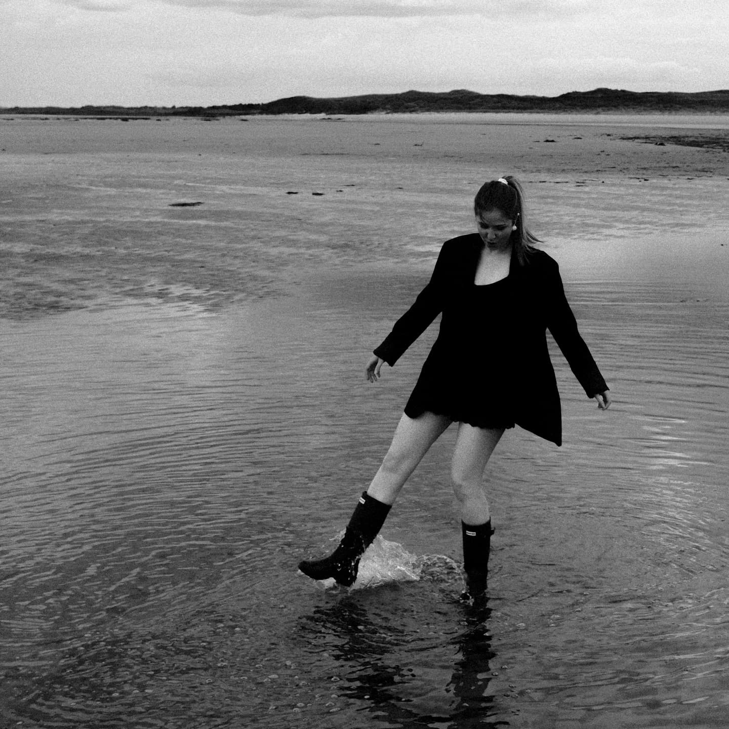 Daryna mid-stride on an Irish beach in a black outfit and boots
