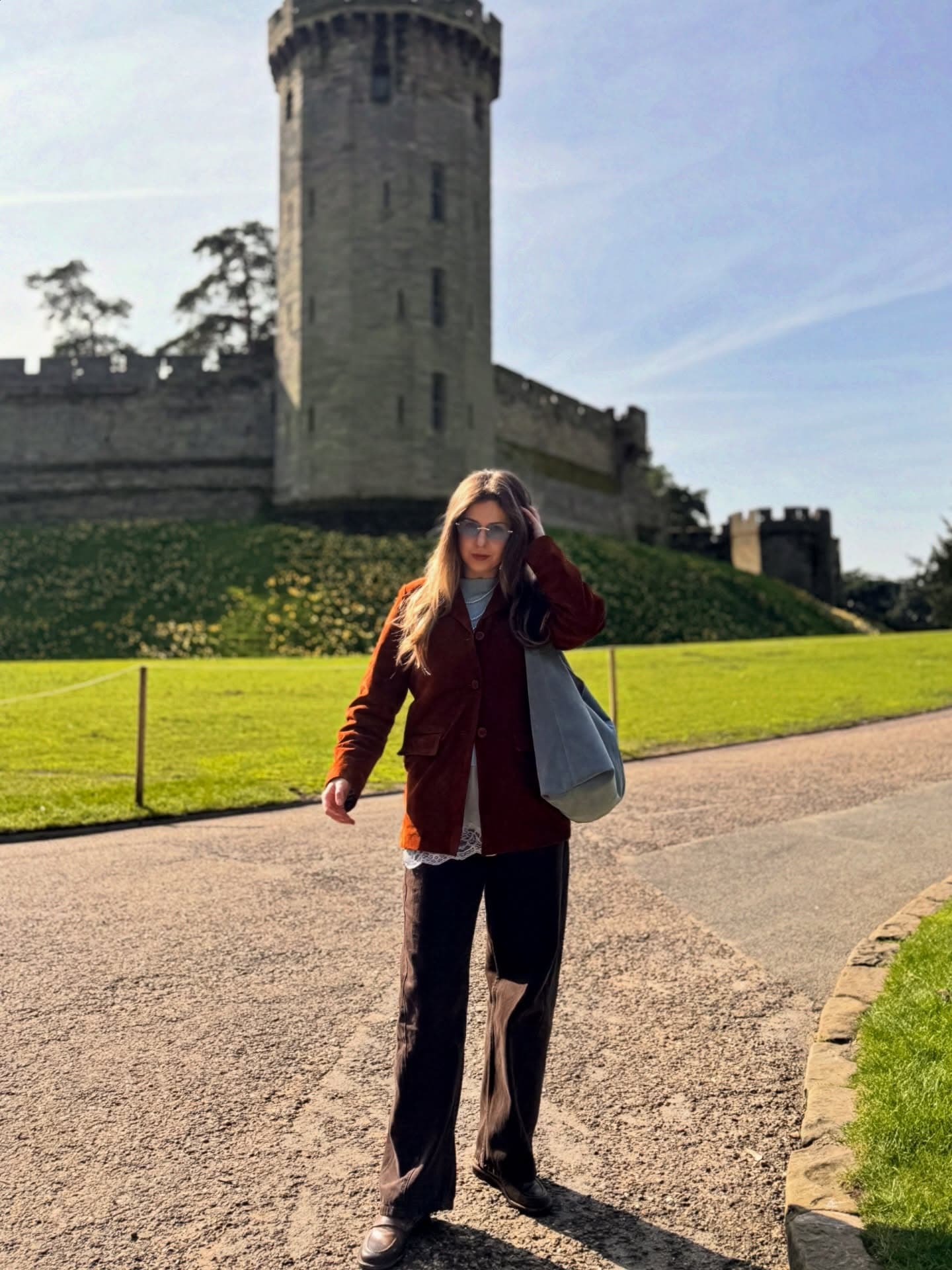 Daryna standing in front of Warwick Castle in a rust blazer
